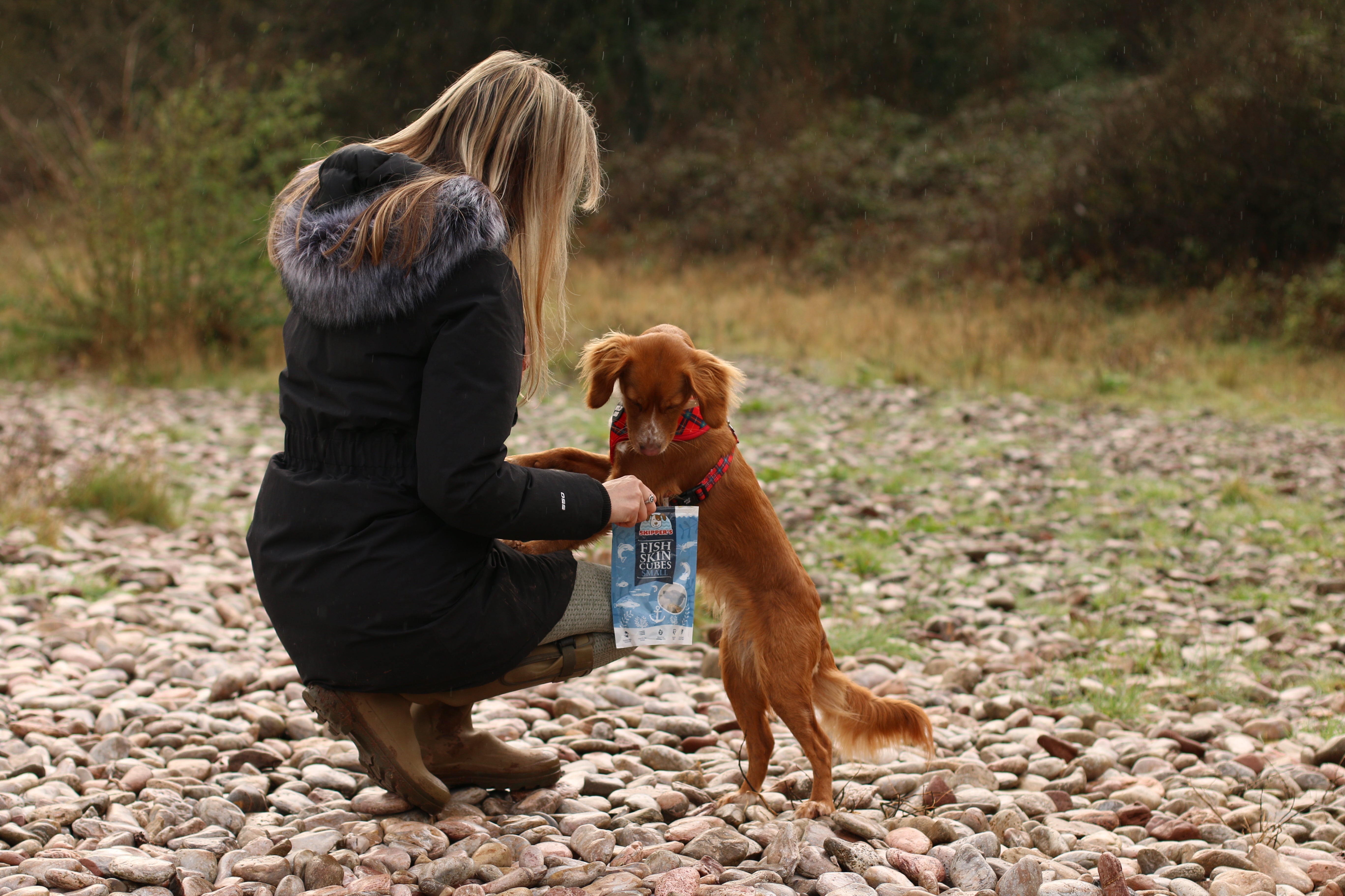 Owner and dog out on a walk with a bag of Skipper's treats