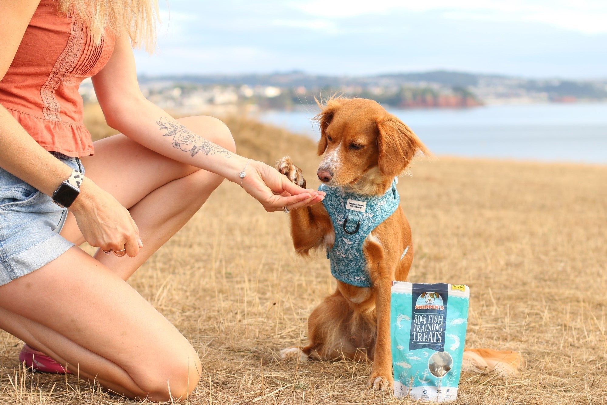 Owner and dog outside with a bag of Whitefish & Herb Sausages