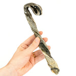 A hand holding a Skipper's Fish Skin Candy Cane dog treat infront of a white background